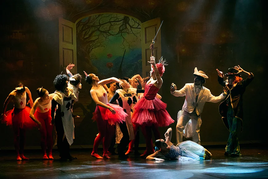 Dotze ballarins i ballerina a escena, vestits com diversos personatges d'Alícia al país de les meravelles