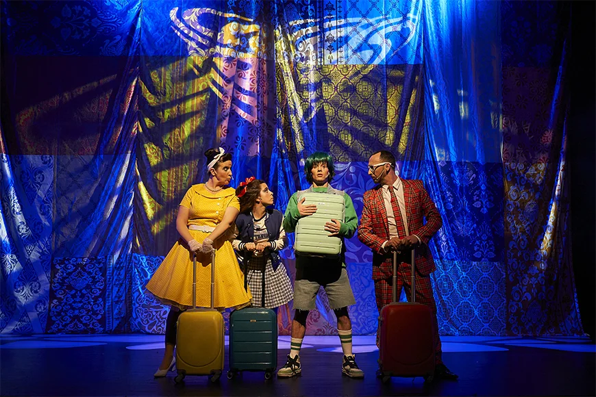 Escena de l’espectacle on la família porta maletes i parlen entre ells.