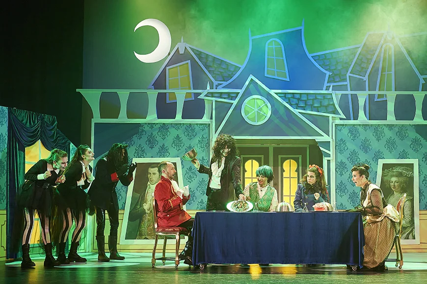 Escena de l’espectacle on la família seu a taula i els porten plats de menjar terrorífics.