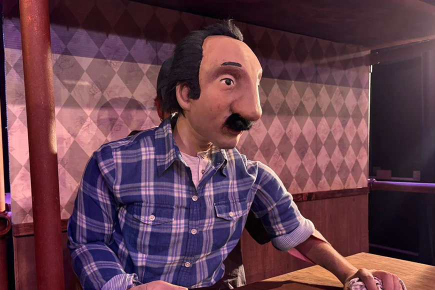 Un titella que representa un home frega el taulell d'un bar.