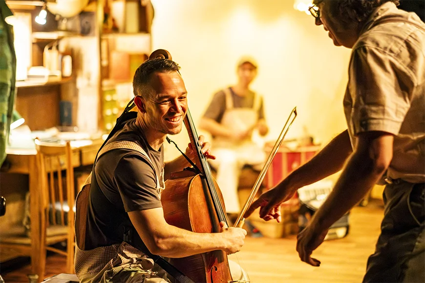 Un noi toca el violoncel i somriu.