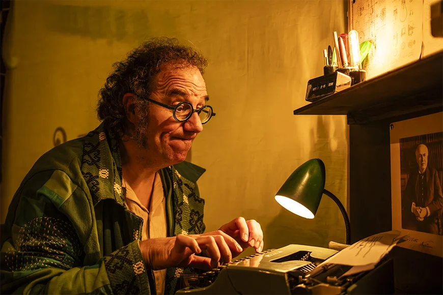 Un home amb ulleres escriu amb una màquina d'escriure antiga.