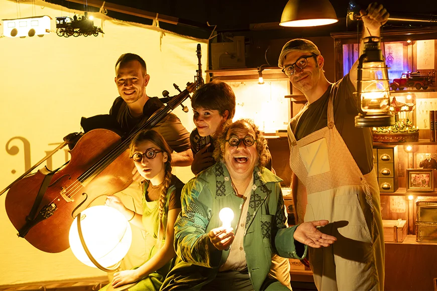 Cinc actors miren a càmera en una foto promocional de l'espectacle. Un porta un violoncel i, un altre un fanal, un altre una làmpara i un darrer una bombeta.
