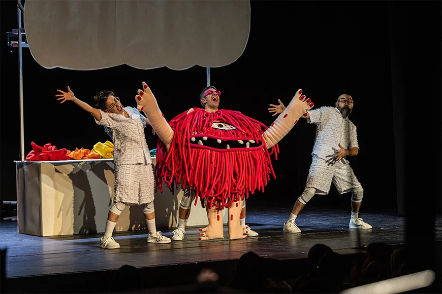 Tres actors i un peluix gegant del Monstre Rosa ballen i canten sobre l'escenari.