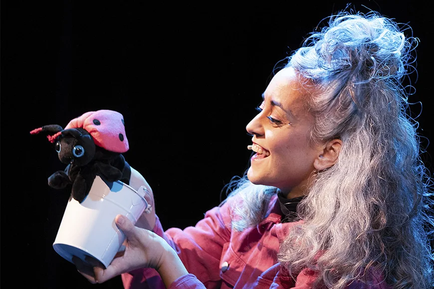 La protagonista de l'espectacle mira somrient la marieta de titella que manipula.